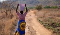 A woman carrying a water bucket on her head in rural Malawi