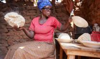 Aline Nibogora sits on a chair in her kitchen preparing ugali (a mixture of maize flour and water cooked over a period of time)