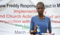 Woman holding supplies. Distribution of materials to communities affected by the Cyclone Freddy that landed in Malawi in March 2023. More than 1000 people died and over 80000 were displaced as houses were damaged rendering these people homeless.