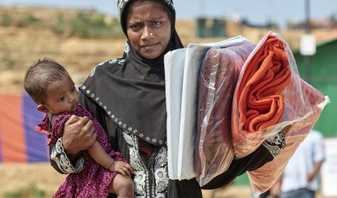 A Rohingya woman carries a tarp, blankets and other items that she received from Christian Aid in the Jamtoli Refugee Camp near Cox's Bazar, Bangladesh. Christian Aid is a member of the ACT Alliance