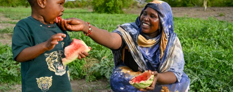 Amani feeds watermelon to her 3-year-old son Badu.