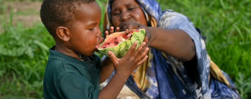 Amani feeds watermelon to her 3-year-old son Badu.