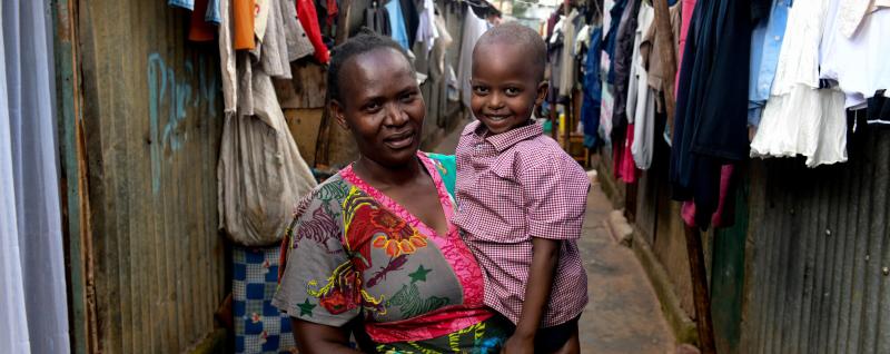  Fridah and her Grandson Quillan outside their home