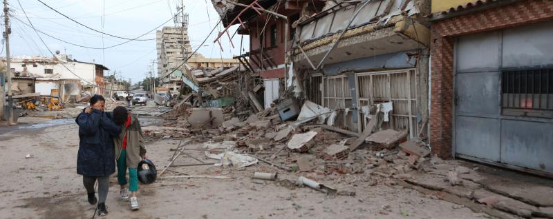 Resident walk past damaged buildings after an earthquake in La Guaira, Venezuela, Thursday, June 25, 2026